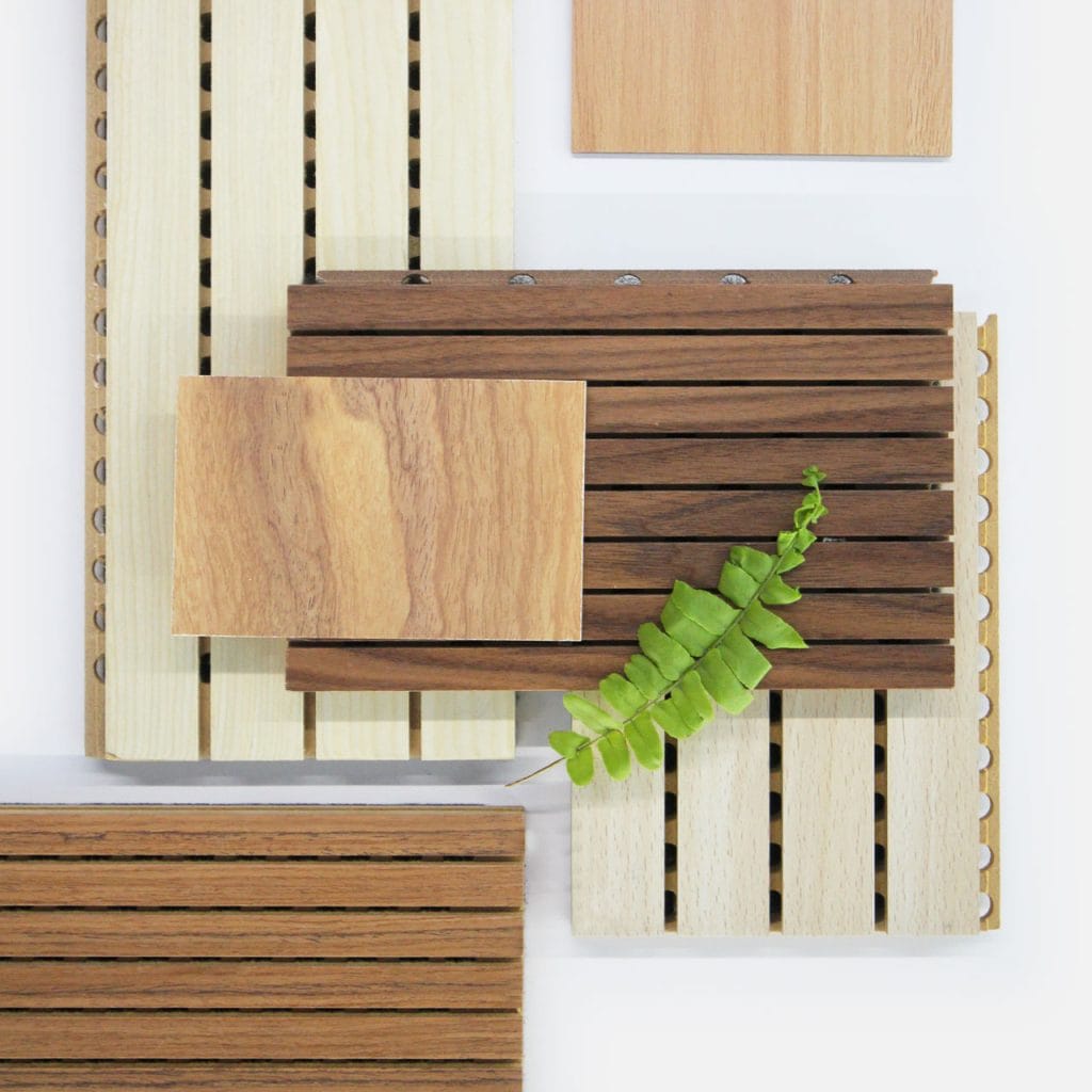 A flat lay of various fire-safe timber cladding panels in different shades and finishes, arranged neatly with a green fern leaf placed on top of one panel—showcasing safety without sacrificing craft.